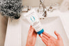 Person holding a bottle of 'Original Sprout Deep Conditioner' in front of a sink.