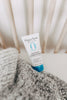 Tube of Original Sprout leave-in conditioner on a textured surface with wooden slats in the background