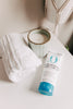 Tube of Original Sprout Scrumptious Baby Cream with a candle and towel on a neutral background